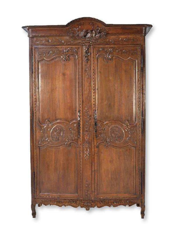 A FRENCH PROVINCIAL ARMOIRE, France, Eighteenth Cen: A FRENCH PROVINCIAL ARMOIRE France, Eighteenth Century The gently arched cornice with carved leaf border above two carved birds sitting on a pair of crossed quivers with arrows, above two rectangular 