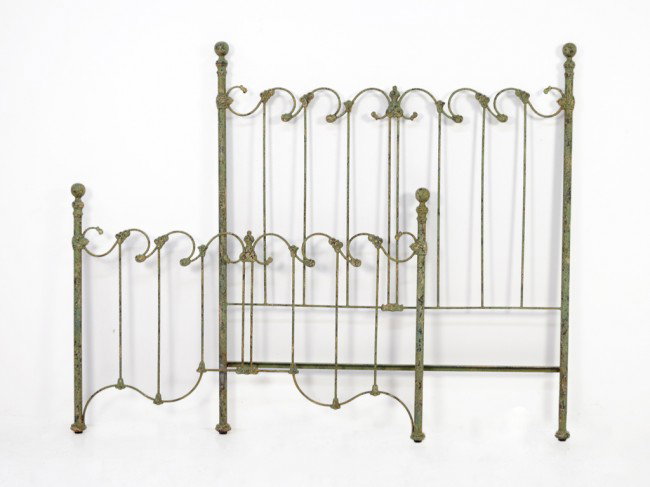 AN ANTIQUED PAINTED IRON BED: AN ANTIQUED PAINTED IRON BED with ball posts flanking a scroll crested top on thin round rails Length 61 in; width 55 in