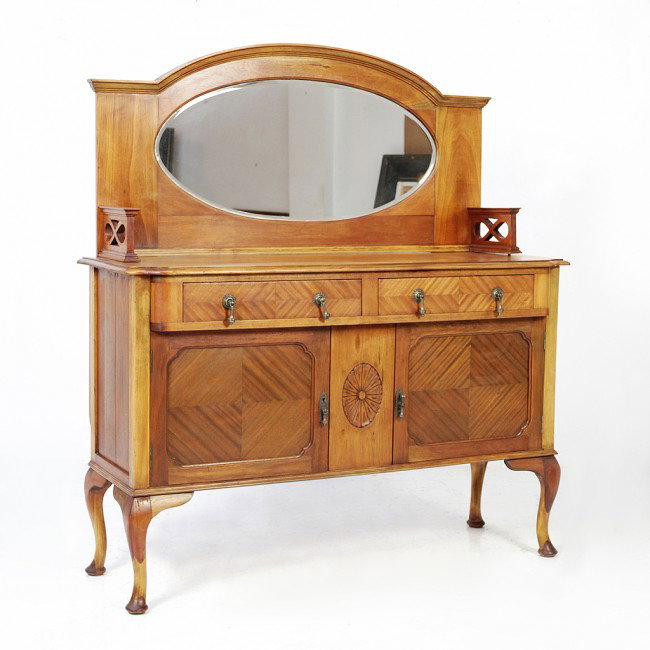 A MAHOGANY SIDEBOARD WITH CENTRAL OVAL BEVELED MIR: A MAHOGANY SIDEBOARD WITH CENTRAL OVAL BEVELED MIRROR with two drawers and two doors with quarter panel angular veneer, the doors flanking a centrally carved rosette, with original brass hardware, rai