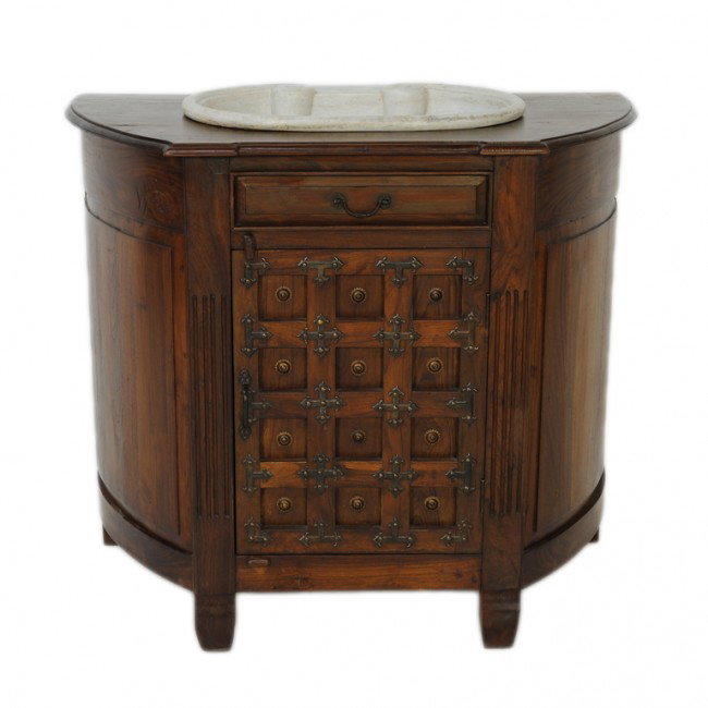 A TEAKWOOD VANITY WITH ITALIAN MARBLE SINK: A TEAKWOOD VANITY WITH ITALIAN MARBLE SINK, Nineteenth Century The sides bowed, with a medieval style caged lower door with cruciform accent brackets, a raised sunburst brass nail head accents to inde