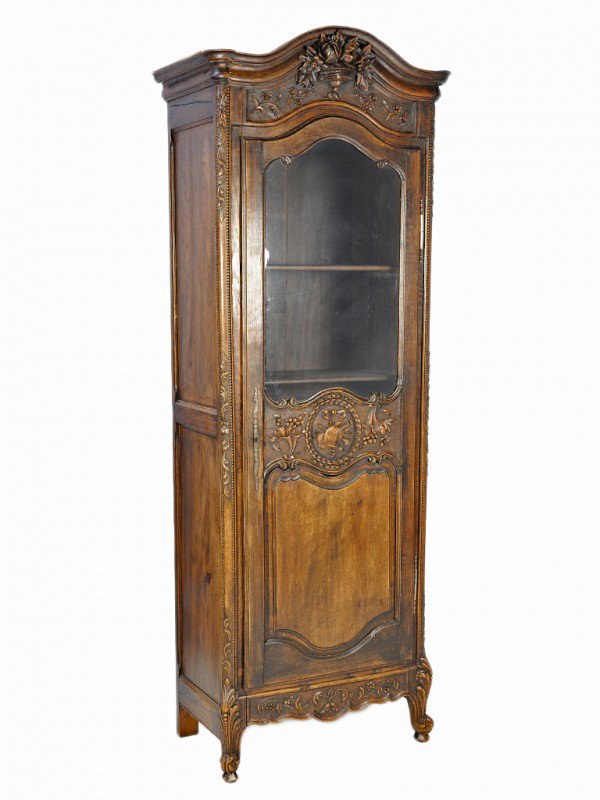 A NORMANDY LOUIS XV OAK BONNETIERE, France: A NORMANDY LOUIS XV OAK BONNETIERE France, First Quarter Nineteenth Century The domed and moulded cornice, above a relief carved flowering urn surrounded by meandering vines frieze; the single door wi