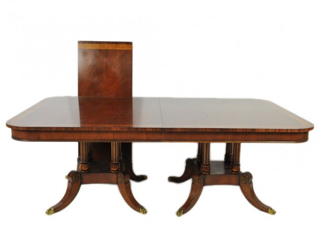 A HENREDON MAHOGANY TABLE WITH BANDS OF WALNUT AND: A HENREDON MAHOGANY TABLE WITH BANDS OF WALNUT AND SATINWOOD with 2 leaves; double crossbanding and ebony stringing to D-end top; on two pedestals with four columnar outswept splay legs; on brass cast