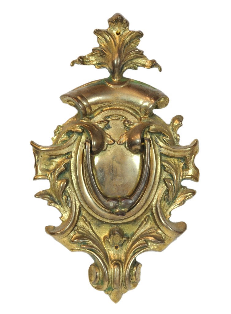 A BRASS DOOR KNOCKER, Twentieth Century: A BRASS DOOR KNOCKER Twentieth Century With cartouche shaped back plate and leaf finial. 12 x 7 ½ x 1 inches