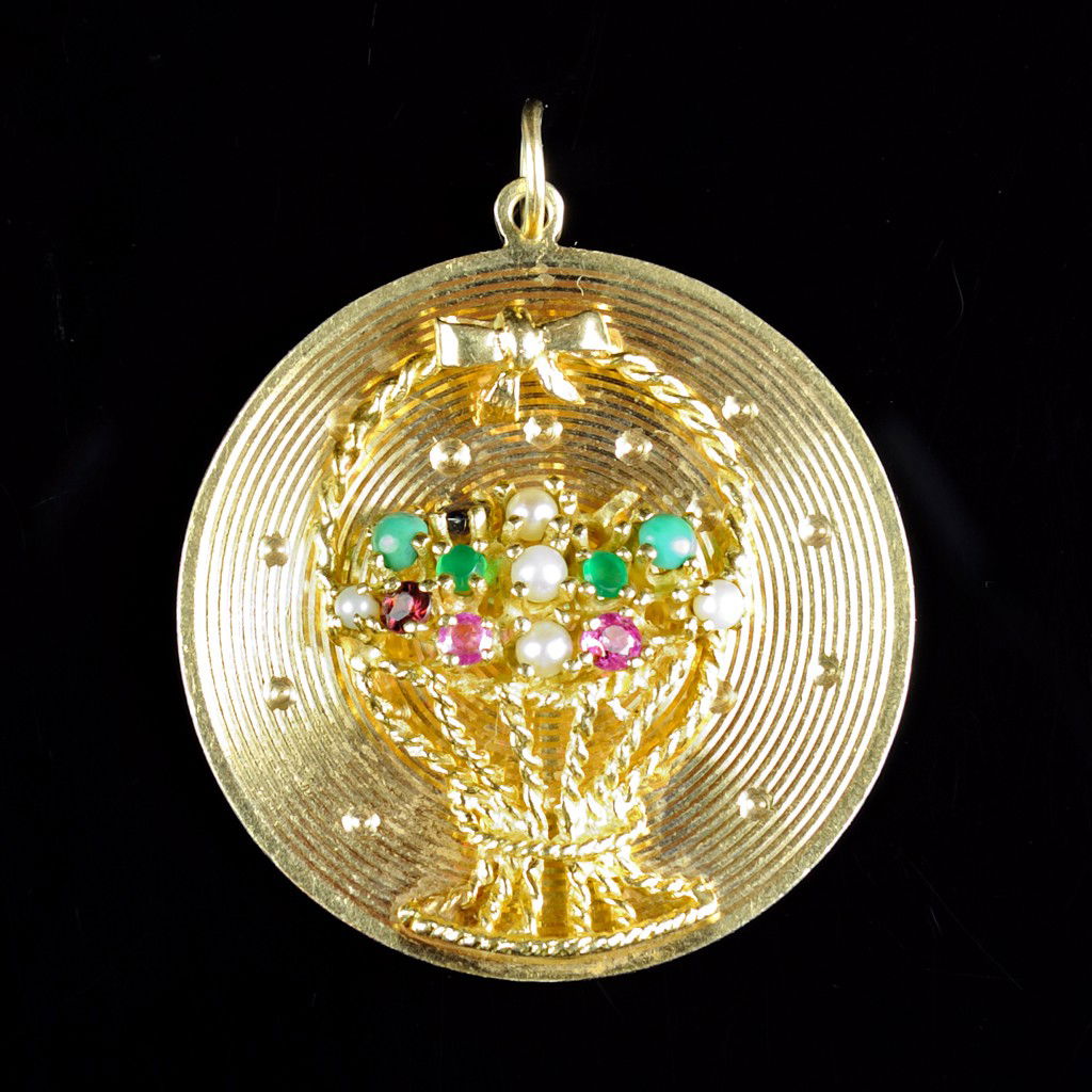 14KT FLORAL DISC: 14KT FLORAL DISC In yellow gold. 1 3/8" in diameter, with engine turned pattern and basket with bow containing pearls, emeralds, rubies, turquois, and sapphires. 12.8 grams.