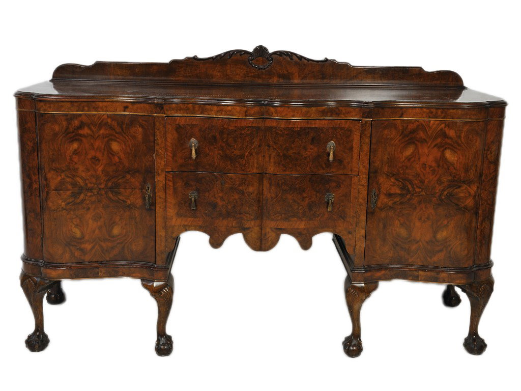 AN EDWARDIAN CHIPPENDALE SHAPED WALNUT SIDEBOARD: AN EDWARDIAN CHIPPENDALE SHAPED WALNUT SIDEBOARD the back splash with relief carved shell and foliate garland; with burl veneer to top and side panels; sweetheart shaped serpentine central drawers fla