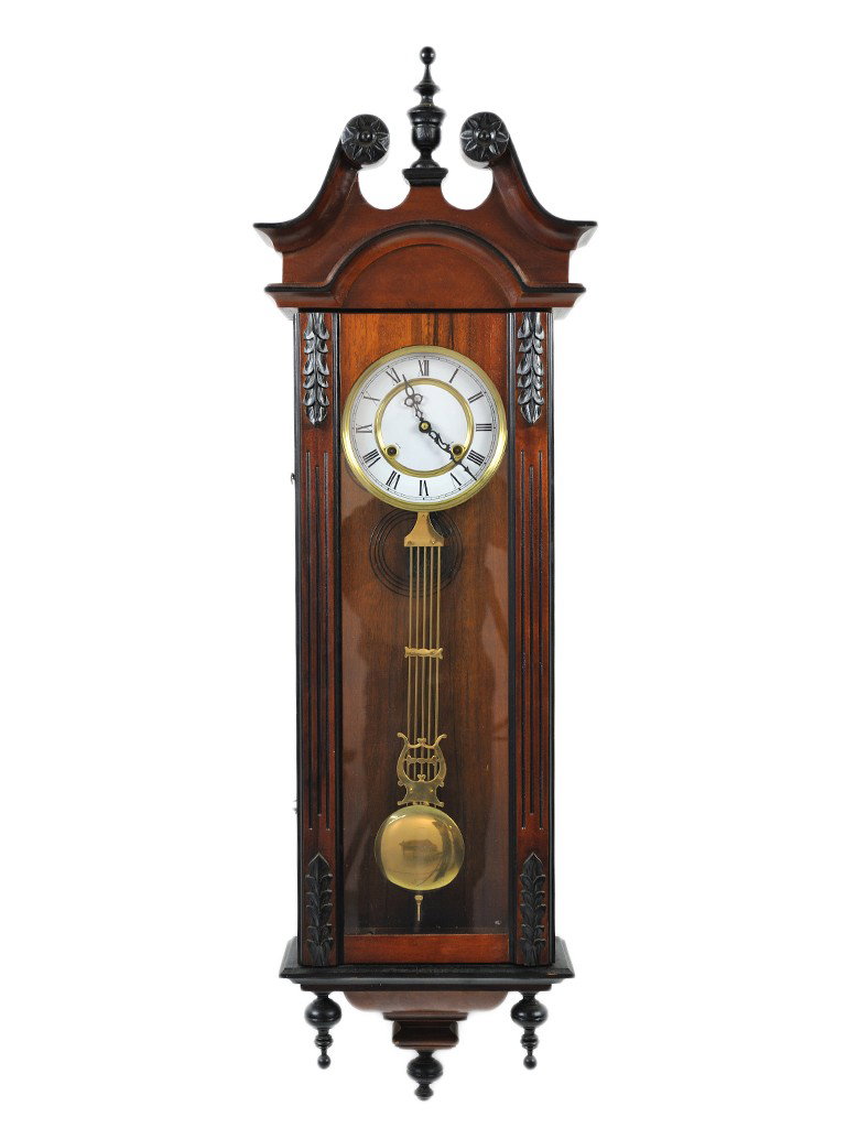 A MAHOGANY WALL CLOCK, Twentieth Century: A MAHOGANY WALL CLOCK Twentieth Century with enamel dial; glass case; carved arched brechiated cornice with carved sunburst medallions to scrolled top; laurel leaf carved applications on reeded side s