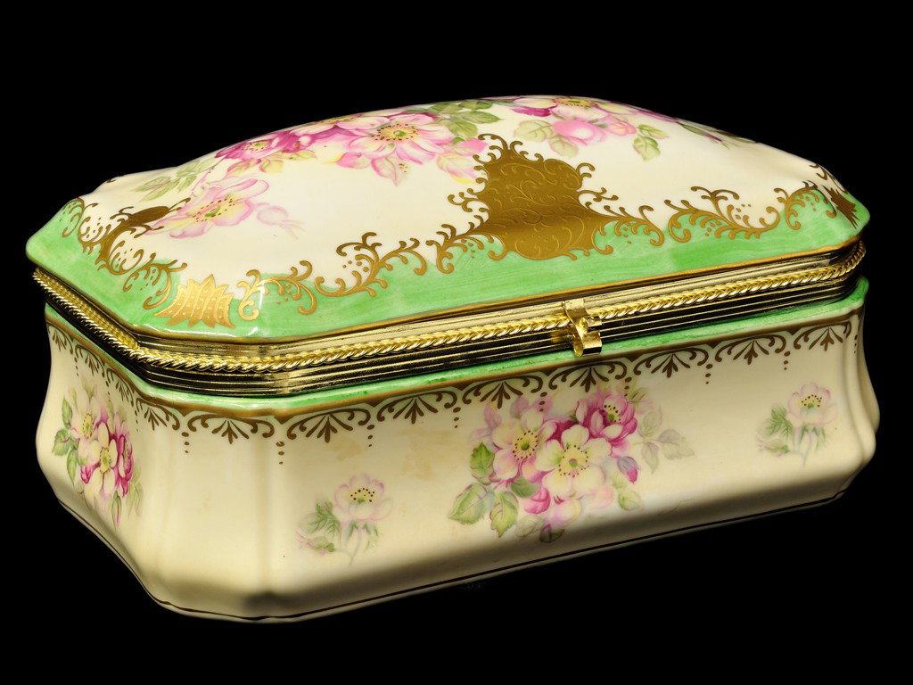 A NIPPON PORCELAIN JEWELRY CASKET: A NIPPON PORCELAIN JEWELRY CASKETwith transfer painted floral decorations; a hand painted green border and gilt details; the floral decorations repeated to inside lid and lower inside surface; gilt br