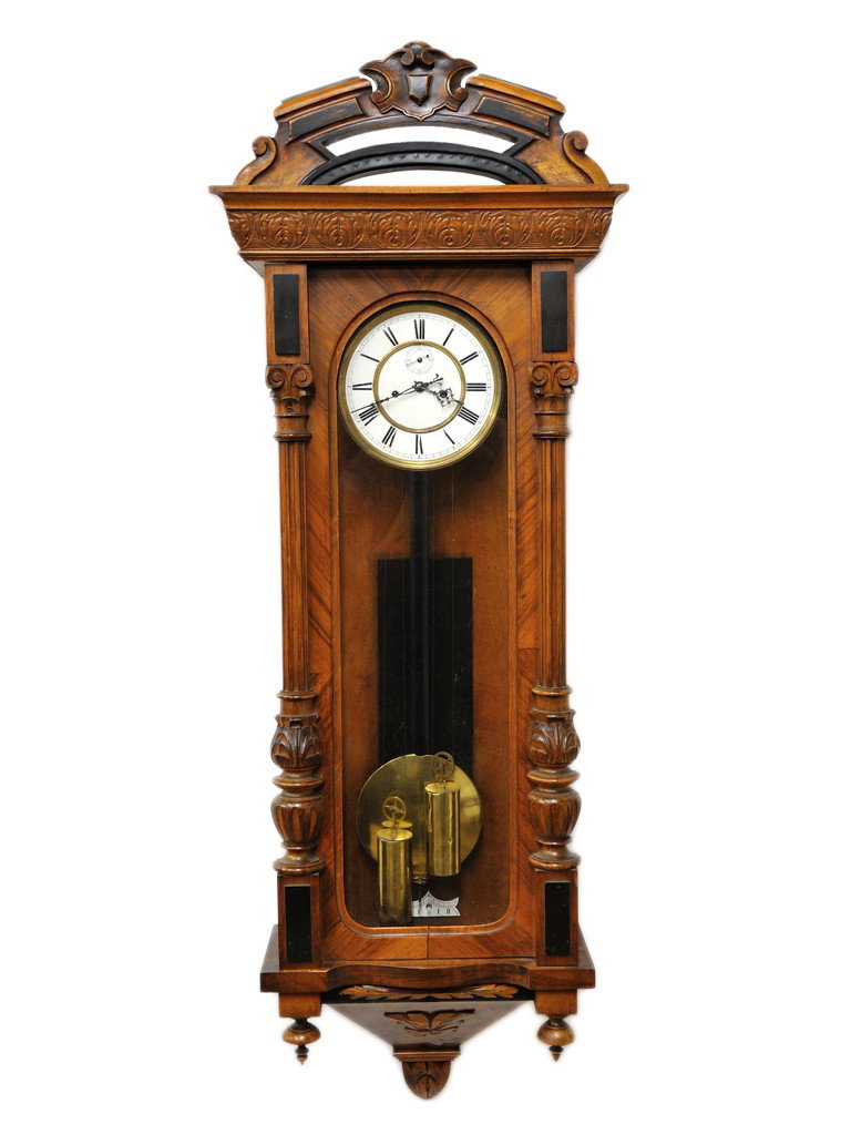 AN AMERICAN WALNUT WALL CLOCK, Driskill Clock Serv: AN AMERICAN WALNUT WALL CLOCK, Driskill Clock Servicewith tall glass case; enameled brass Roman numeral face; pierced arched crest, dated 12-6-76 48 x 17 x 7 inches