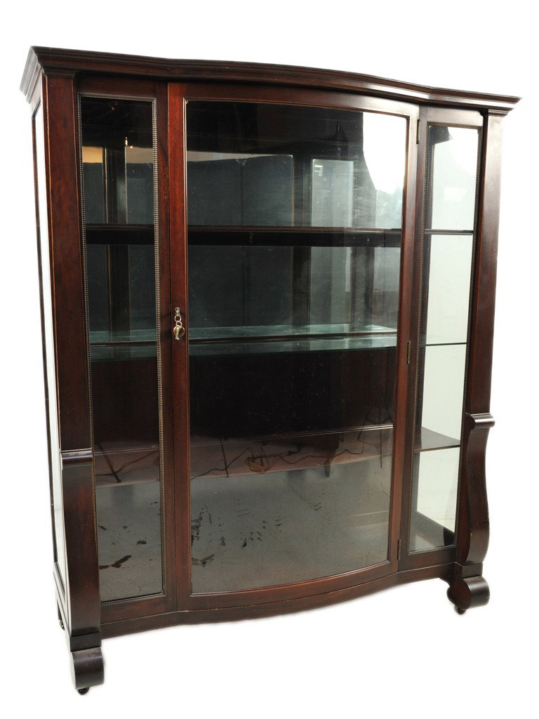 AN AMERICAN EMPIRE MAHOGANY BOW-FRONT DISPLAY CASE: AN AMERICAN EMPIRE MAHOGANY BOW-FRONT DISPLAY CASE, Late 19th Century the moulded cornice above the original glazed ends; pair of sidelights and bow-front single door; having a mirrored back above the