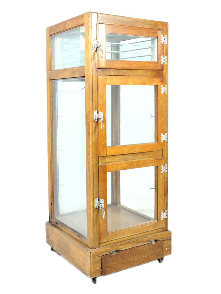 AN AMERICAN OAK AND GLASS TRIPLE DOOR DISPLAY ICE: AN AMERICAN OAK AND GLASS TRIPLE DOOR DISPLAY ICE BOX, Late 19th-Early 20th Century the stained oak case having original glazing and brushed steel hardware on plinth base with hinged compartment for d