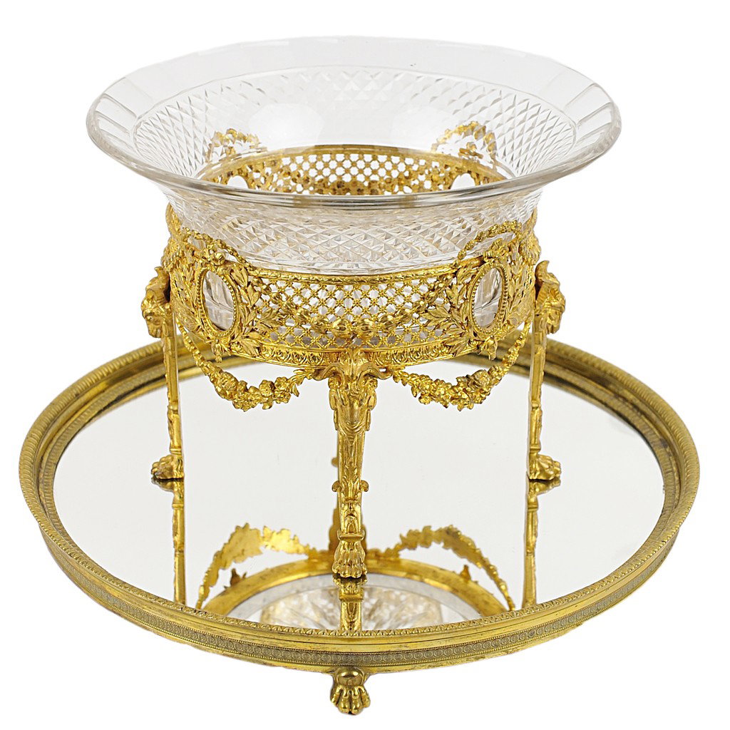 A FRENCH EMPIRE CUT CRYSTAL BOWL ON DORE BRONZE PLI: A FRENCH EMPIRE CUT CRYSTAL BOWL ON DORE BRONZE PLINTH France, 1820 reticulated with floral garlands adjacent to ram's head. Figured legs on raised paw feet. Bowl 9 ½ inch (24.1 cm) diameter; Plinth 