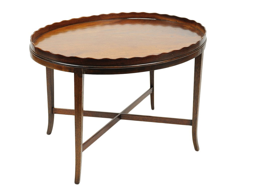 A MAHOGANY OVAL TRAY WITH PIE CRUST EDGE ON STAND: A MAHOGANY OVAL TRAY WITH PIE CRUST EDGE ON STAND The pie crust gallery on a figured mahogany oval tray; raised on a recessed stand with flaring square section legs and plain X-form stretcher. 20 x 29