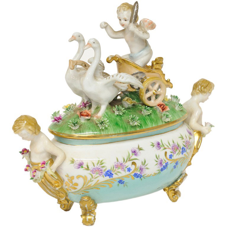 A SMALL SÈVRES STYLE GILDED AND DECORATED PORCELAI: A SMALL SÈVRES STYLE GILDED AND DECORATED PORCELAIN FIGURAL TUREEN WITH LID The oval tureen lid having an elaborately modeled scene depicting a putto standing in a chariot drawn by two geese in a fie