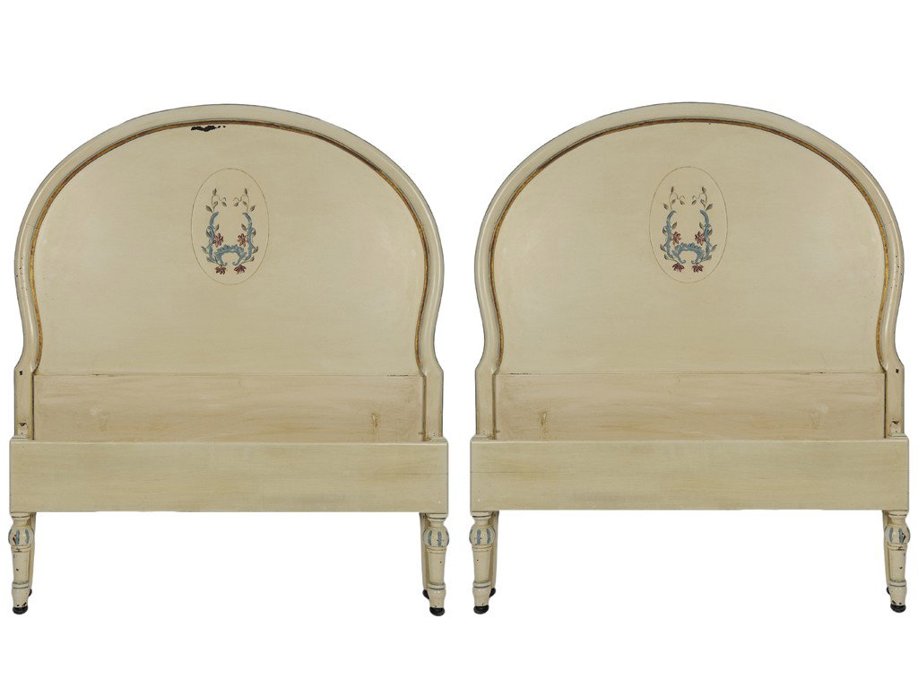 A PAIR OF HAND-PAINTED TWIN BEDS Circa 1920: A PAIR OF HAND-PAINTED TWIN BEDS Circa 1920 Arched molded crest rail with center panel painted ivory with hand-decorated gold trim and pair of foliate pendant garlands; raised on carved legs with cast