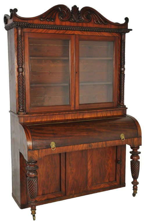 AN AMERICAN CLASSICAL MAHOGANY SECRETARY c. 1830: AN AMERICAN CLASSICAL MAHOGANY SECRETARY c. 1830 a finely carved scrolled pediment creating the image of horns emitting sound, supported by a pair of carved mahogany columns flanking a pair of glass d