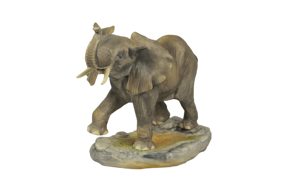 A SIGNED BOEHM BISQUE PORCELAIN FIGURE OF AN ELEPHAN: A SIGNED BOEHM BISQUE PORCELAIN FIGURE OF AN ELEPHANT CALF American, 20th Century The matte-painted figure of a baby elephant depicted in a playful pose with trunk and right foot raised and ears flopp
