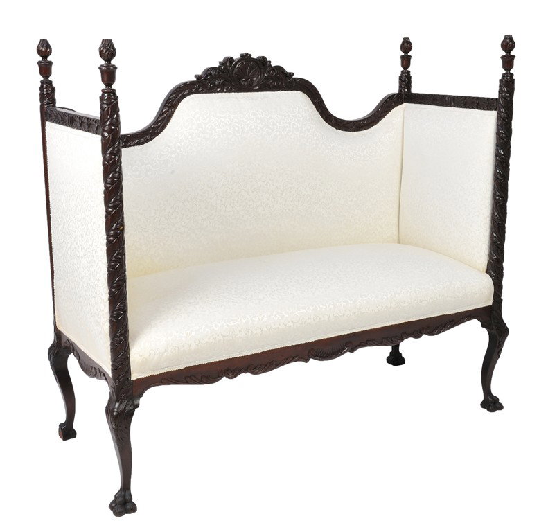 A MAHOGANY PARTIONED HIGHBACK UPHOLSTERED SETTEE: A MAHOGANY PARTIONED HIGHBACK UPHOLSTERED SETTEE The carved shell crest with shaped crest rail with relief carving of acanthus vine and four truncated flare and urn finials supported by spiral carved 