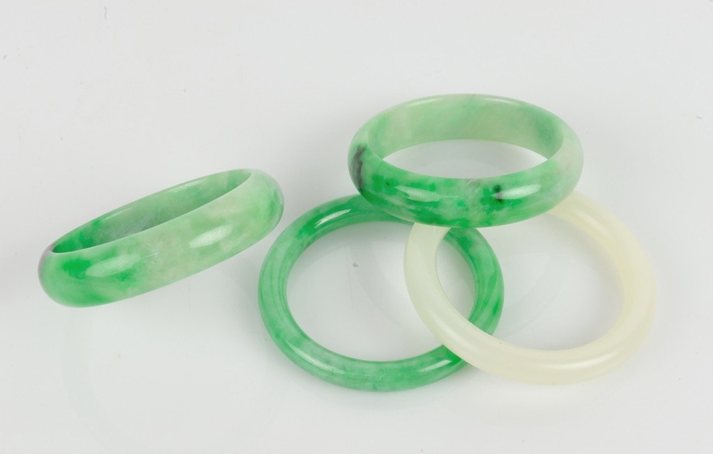 FOUR CHINESE CARVED JADE BANGLES: FOUR CHINESE CARVED JADE BANGLES ½ x 3 x 3 inches