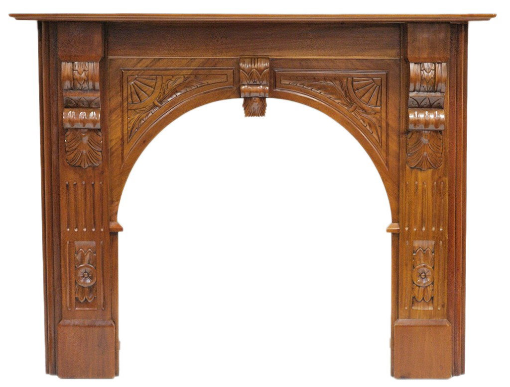 A HAND CARVED MAHOGANY FIREPLACE SURROUND: A HAND CARVED MAHOGANY FIREPLACE SURROUND Carved corbel support the mantle shelf and elongate down the front into a pilaster form with block foot. The arched firebox has carved panel detail and center