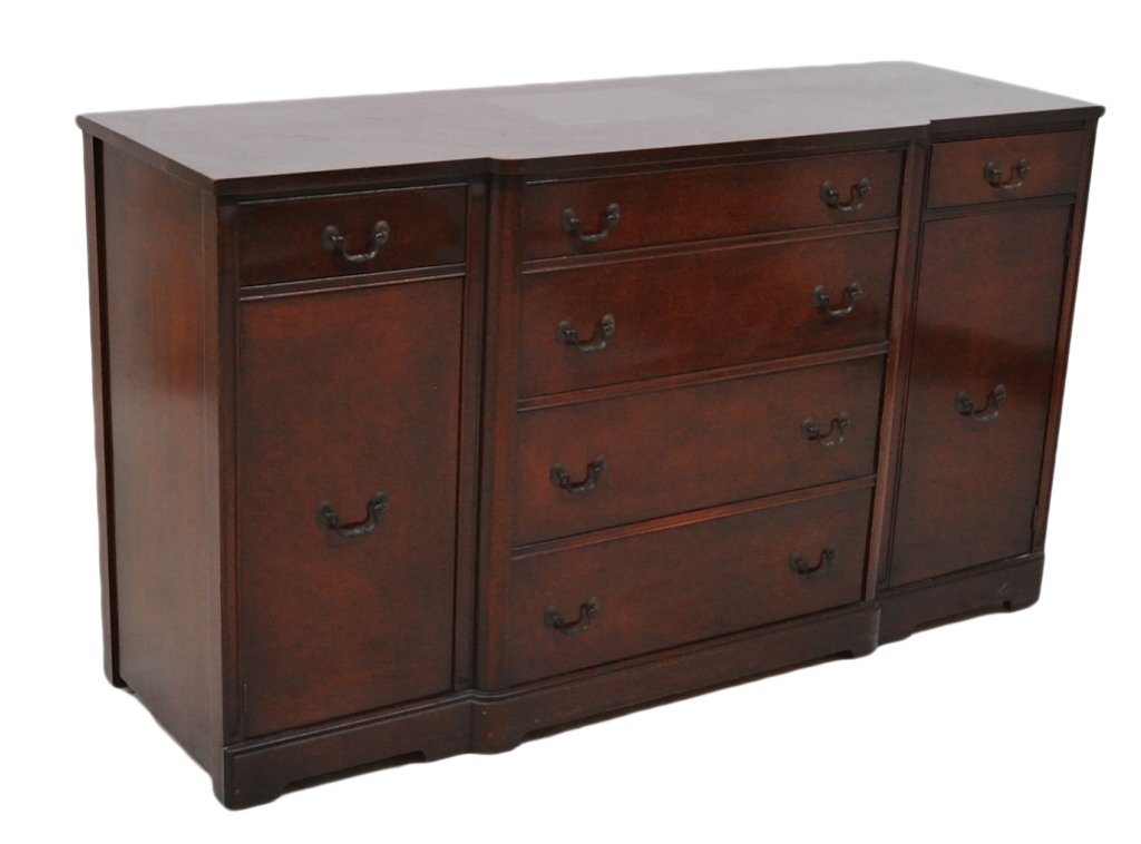 A MID CENTURY SHERATON STYLE MAHOGANY SIDEBOARD: One small upper drawer divided and lined for flatware. Two large storage compartments with shelf over a single door flank a center section of storage drawers. 36 x 64 x 21 inches