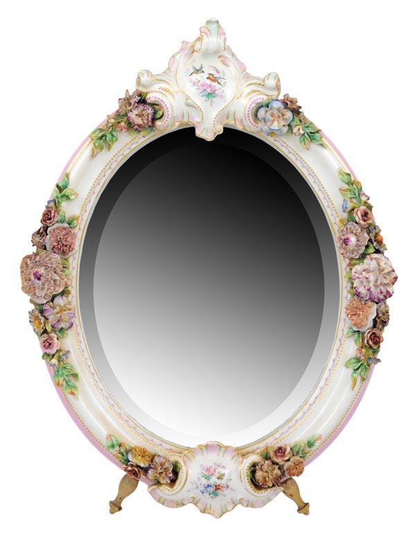 A MEISSEN STYLE OVAL PORCELAIN VANITY MIRROR 20th C: A MEISSEN STYLE OVAL PORCELAIN VANITY MIRROR 20th Century The hand painted shield surmounts a floral encrusted and parcel gilt frame inset with a beveled mirror, wood back with wooden easel stand. Mar