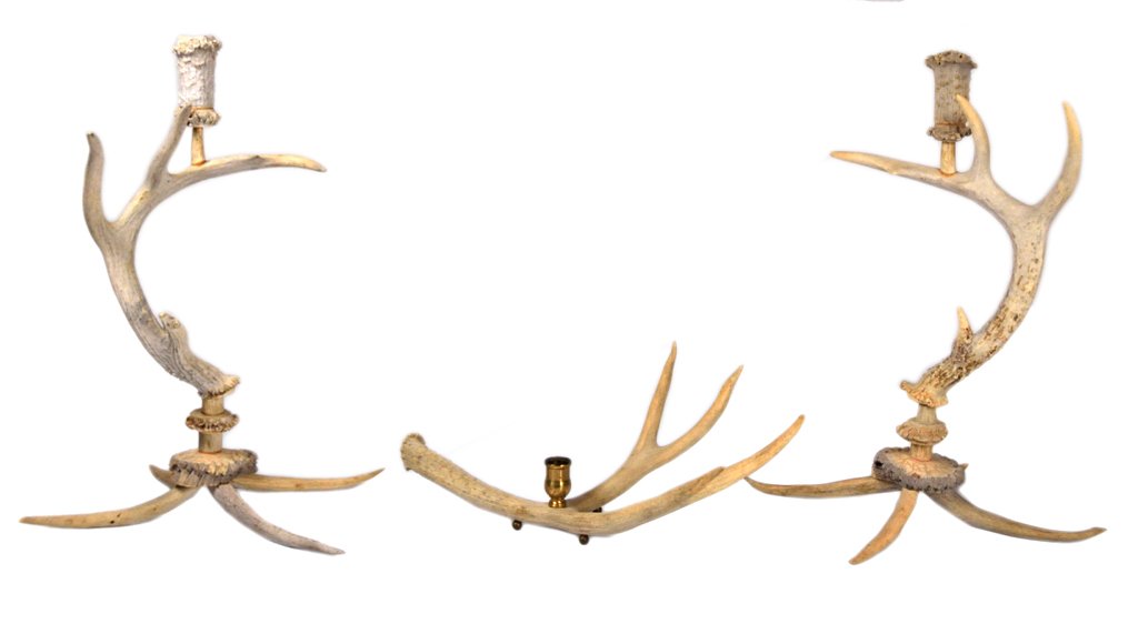 A SET OF THREE DEER ANTLER CANDLESTICKS: A SET OF THREE DEER ANTLER CANDLESTICKS 20th Century The set consisting of two tall and one short candlestick, the latter with a brass candle cup. Natural antler. Tallest: 10 ¾ x 13 ¼ x 10 7/8 inche