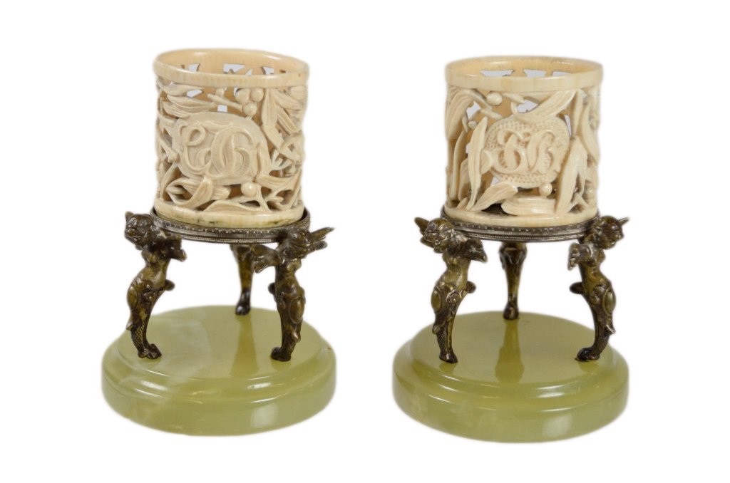 A PAIR OF IVORY AND ONYX CIGARETTE HOLDERS: A PAIR OF IVORY AND ONYX CIGARETTE HOLDERS Austria, 19th- 20th Century. Each holder consisting of a monogrammed oval pierce-carved ivory container set in a patinated bronze ring supported by three win