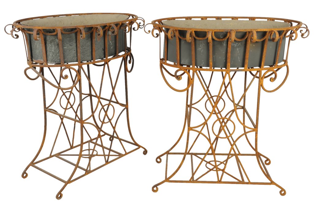 A PAIR OF OVAL WROUGHT IRON PLANTERS WITH TOLE INS: A PAIR OF OVAL WROUGHT IRON PLANTERS WITH TOLE INSERTS American, 20th Century The galvanized tole containers with flared edges are set into wrought iron bases of wrought iron in Neoclassical style. Go