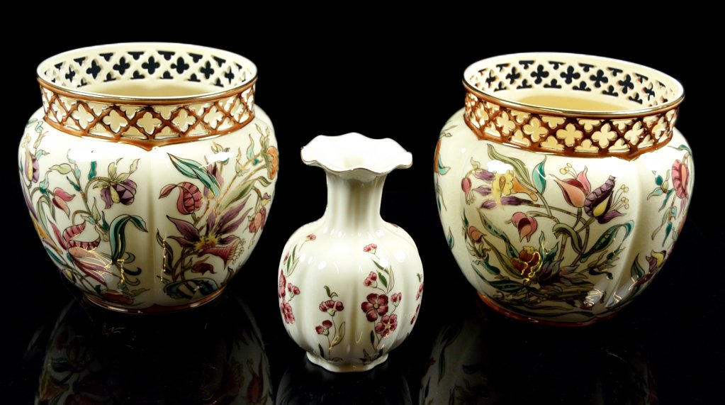THREE ZSOLNAY GILDED PORCELAIN FLORAL CONTAINERS: THREE ZSOLNAY GILDED PORCELAIN FLORAL CONTAINERS Hungarian, 20th Century. Includes a small vase and a pair of small cachpot, all with lobed bodies and floral decoration on a cream ground, the cachpot 