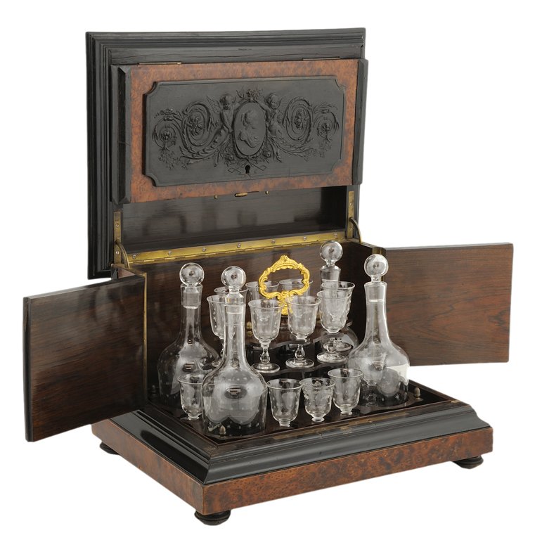 A FRENCH TANTALUS LIQUOR SET WITH FITTINGS 19th Ce: A FRENCH TANTALUS LIQUOR SET WITH FITTINGS 19th Century A burl olive wood tantalus liquor set with ebonized mouldings and figural relief carved appliques all raised on pad feet. Set includes 4 decante