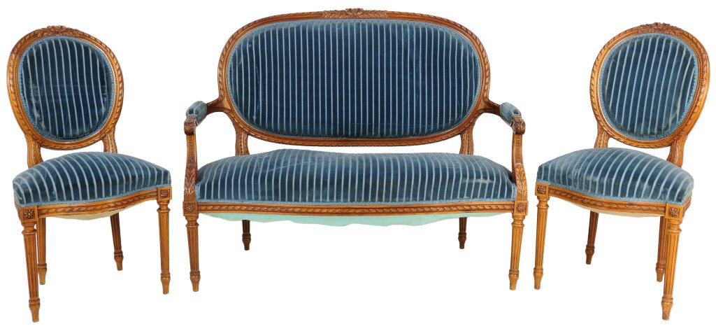 A LOUIS XVI STYLE CARVED WALNUT SALON SET: A LOUIS XVI STYLE CARVED WALNUT SALON SET 19th Century, France A trio of Louis XVI style carved walnut furniture includes two side chairs and a settee crowned by a laurel and berry ribbon at crest rai