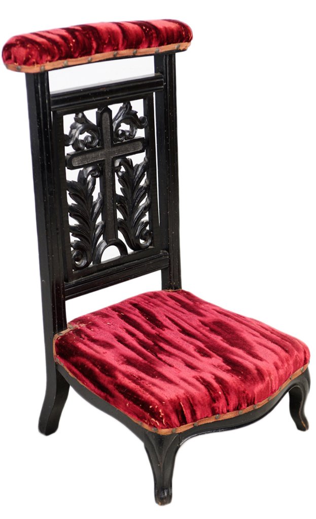 ANTIQUE CARVED AND EBONIZED PRIE DIEU: ANTIQUE CARVED AND EBONIZED PRIE DIEU Late 19th Century, France A red velvet and black prie dieu crowned by a covered arm rest with bronze nail head trim, having a pierce carved scrolling acanthus cro