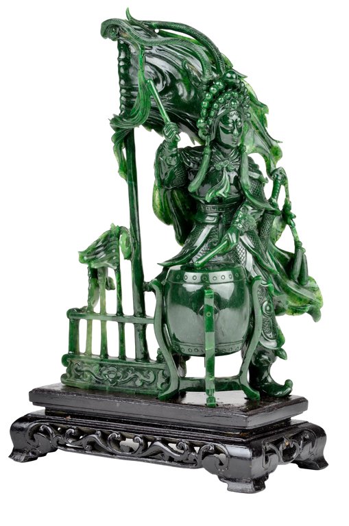 A CHINESE SPINACH GREEN HARDSTONE DRUMMER Mid-20th: A CHINESE SPINACH GREEN HARDSTONE DRUMMER Mid-20th Century A warrior beats on a drum with a large flag flying aloft and smaller handheld flags in a stand. Well carved with polished finish. Raised on f
