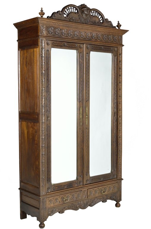 AN ANTIQUE FRENCH BRITTANY STYLE CARVED TWO DOOR ARMOIR: AN ANTIQUE FRENCH BRITTANY STYLE CARVED TWO DOOR ARMOIRE Late 19th - Early 20th Century, France A fine French Brittany style armoire having a fanned spandrel cornice with a center portrait carved meda