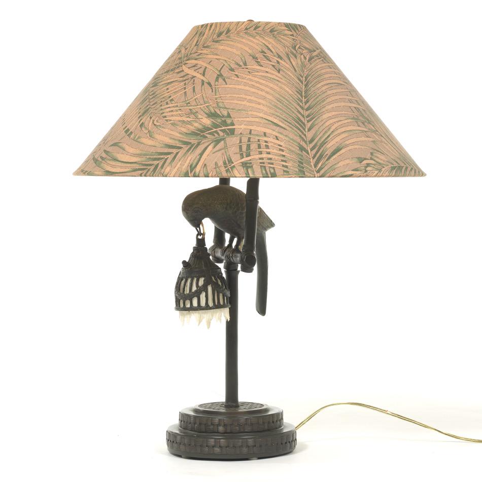 Frederick Cooper Parrot Lamp: 27"H Table lamp with two arms and sockets, depicting a parrot on a perch holding a cage in it's mouth, also a socket for a small bulb. Shade with leaf design. Marked on socket. View and Bid on