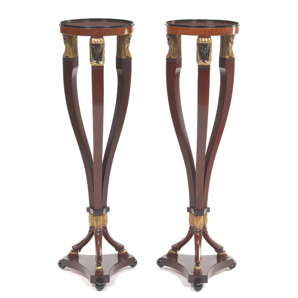 Pair of Egyptian Revival Stands, by Robert Irwin: 39-1/2" x 11-1/4" Egyptian Revival occasional stands, round with Sphinx style tripod base on hoof feet, picked out in gilt with ebonized elements. Irwin labels to the underside. View and Bid on