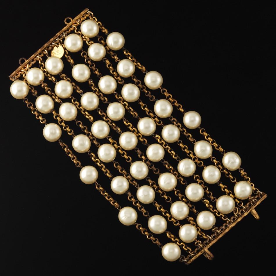 Chanel 10-Strand Faux Pearl Bracelet: 7" x 3 1/4" Chanel gold tone chain link 10-strand faux pearl bracelet with hook closure. Charm label stamped "Chanel, Made in France". View and Bid on AspireAuctions.com