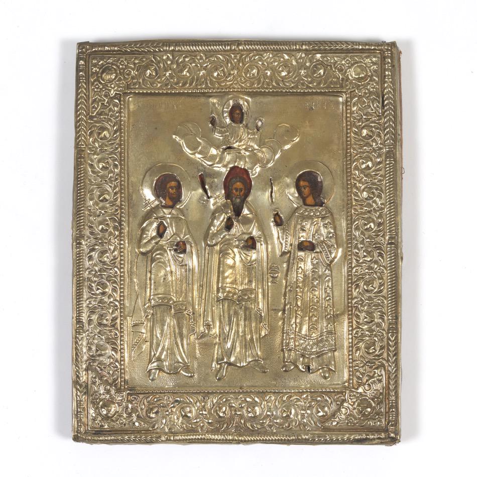 Russian Antique Icon of Three Saints, in Silvered Brass Oklad, ca. 19th Century: 8-3/4" x 7" x 3/4" Rectangular slightly convex shape, hand painted tempera on gessoed wood panel, depicting three saints, in embossed openwork silvered brass oklad, with fabric backing. View and Bid o