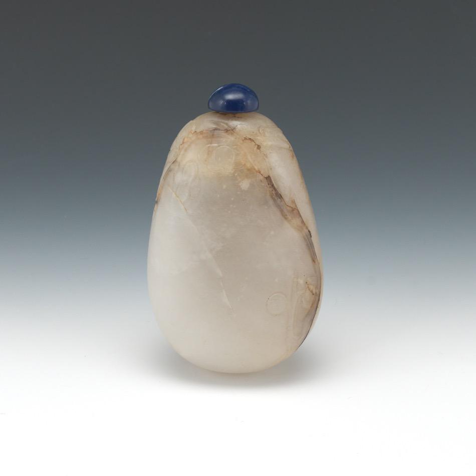 Chinese Mutton Fat Jade Pebble Form Carved Snuff Bottle with Lapis Lazuli Stopper: Hollowed and polished mutton fat jade pebble form snuff bottle, carved along the inclusion lines with a fine blossoming prunus tree, with cabochon carved round lapis lazuli stopper with metal spoon.