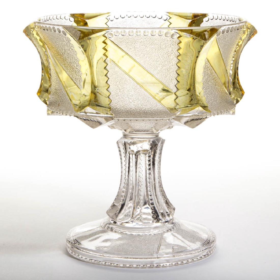 STIPPLED BAR - AMBER-STAINED OPEN COMPOTE: STIPPLED BAR - AMBER-STAINED OPEN COMPOTE, colorless. U. S. Glass Co. Pattern introduced in 1895. 8 1/4" H, 8 1/4" DOA.Nearly undamaged with a few scattered flakes.Provenance: From the collection of t