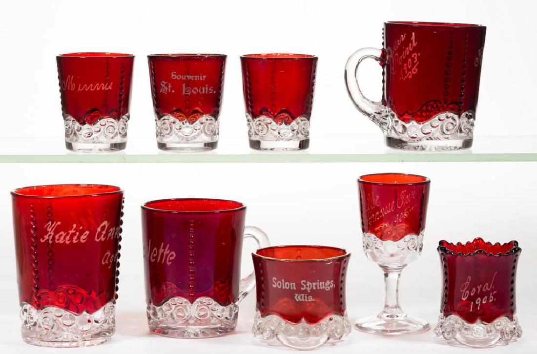 BEAD AND SCROLL - RUBY-STAINED ARTICLES, LOT OF NINE: BEAD AND SCROLL - RUBY-STAINED ARTICLES, LOT OF NINE, colorless, including a tumbler, two mugs, a wine, and a toothpick holder; eight pieces with souvenir decoration. Probably U.S. Glass Co. Circa 189