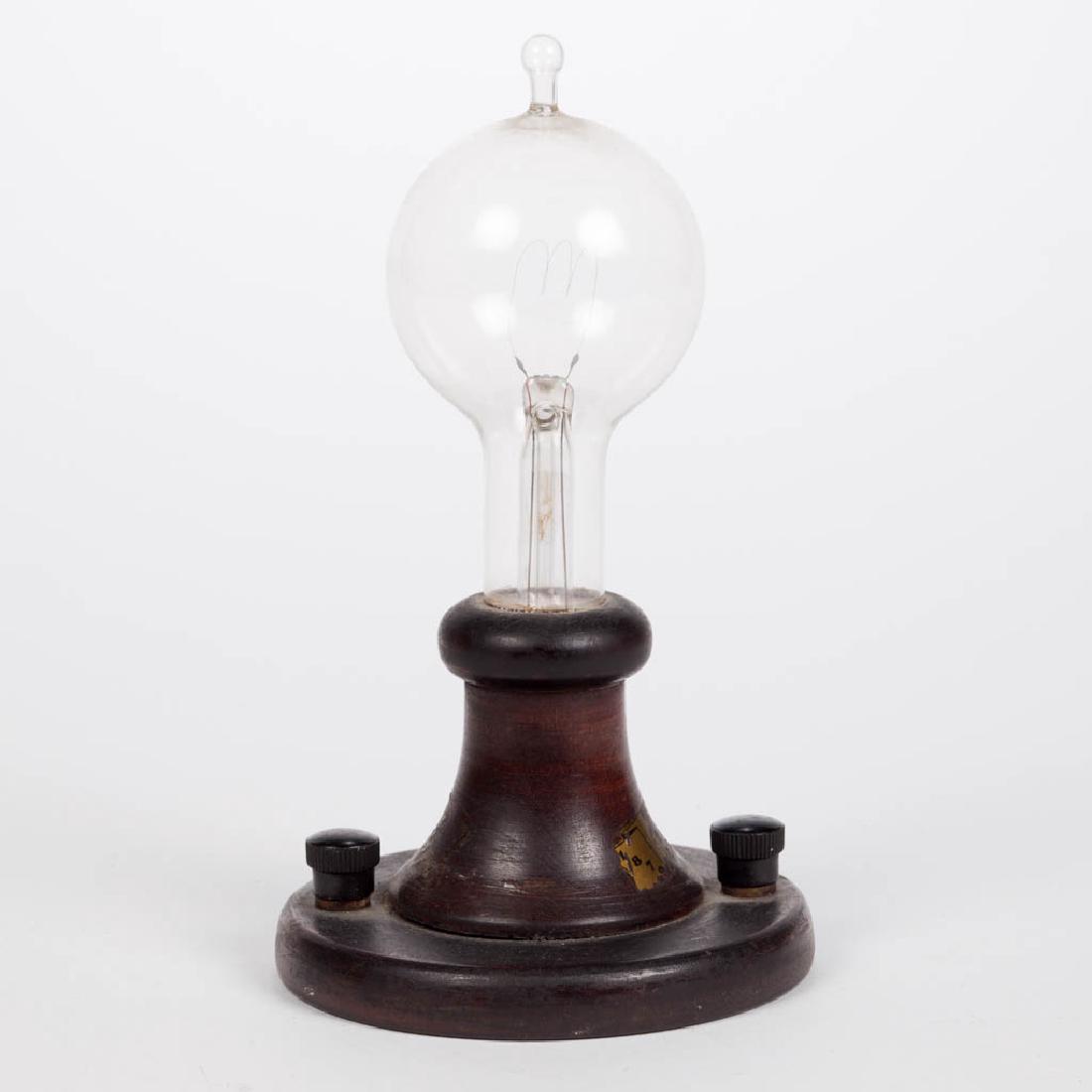 THOMAS EDISON COMMEMORATIVE LIGHT BULB: THOMAS EDISON COMMEMORATIVE LIGHT BULB, original wooden base with two hook ups and original screw caps, remnants of original decal on base. Probably 1929 for the 50th anniversary of Edison's invention
