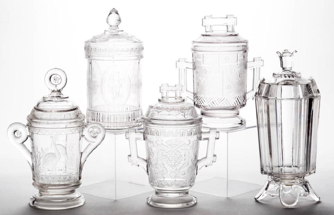 ASSORTED EAPG JAM / PICKLE JARS, LOT OF FIVE: ASSORTED EAPG JAM / PICKLE JARS, LOT OF FIVE, colorless, including Stork with Fish, Cupid and Venus, and Barred Forget-Me-Not. Fourth quarter 19th century. 6" to 8" HOA.Forget-Me-Not with moderate rim