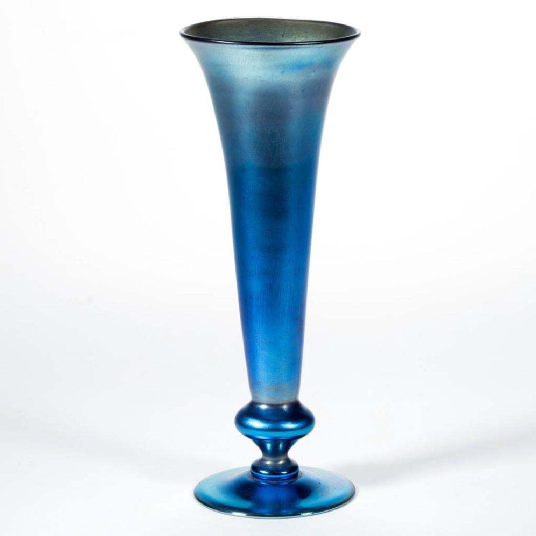 TIFFANY FAVRILE BLUE IRIDESCENT ART GLASS TRUMPET VASE: TIFFANY FAVRILE BLUE IRIDESCENT ART GLASS TRUMPET VASE, bowl connecting to a knop stem and applied circular foot, polished pontil mark, signed, "923 L / L.C.Tiffany - Favrile". Tiffany Studios. 1917.