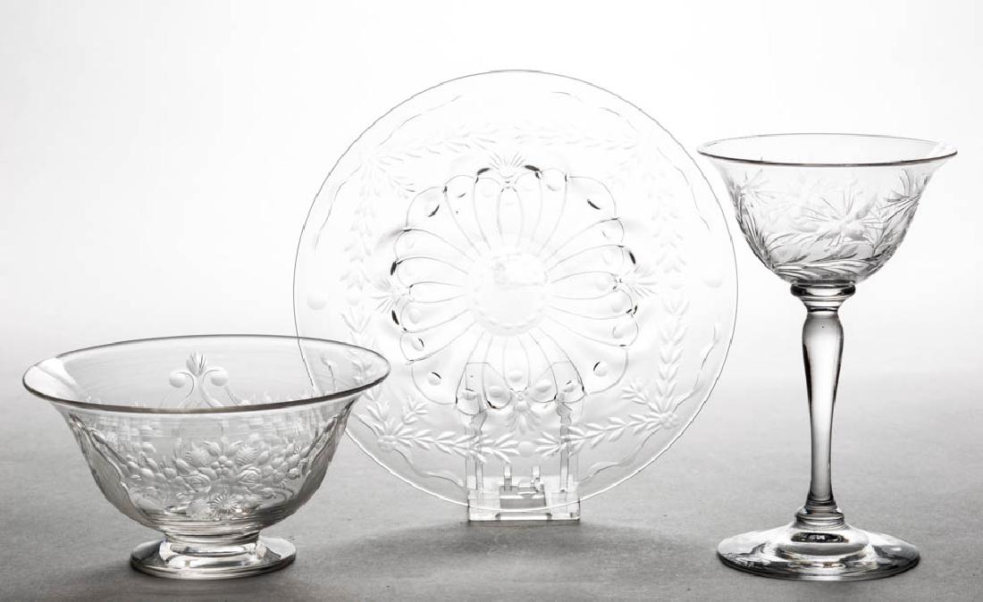 STEUBEN CUT AND ENGRAVED GLASS TABLE ARTICLES, LOT OF: STEUBEN CUT AND ENGRAVED GLASS TABLE ARTICLES, LOT OF THREE, comprising a footed finger bowl with a floral spray swag and figural bottles, a rock crystal underplate, and a wine, two examples with make