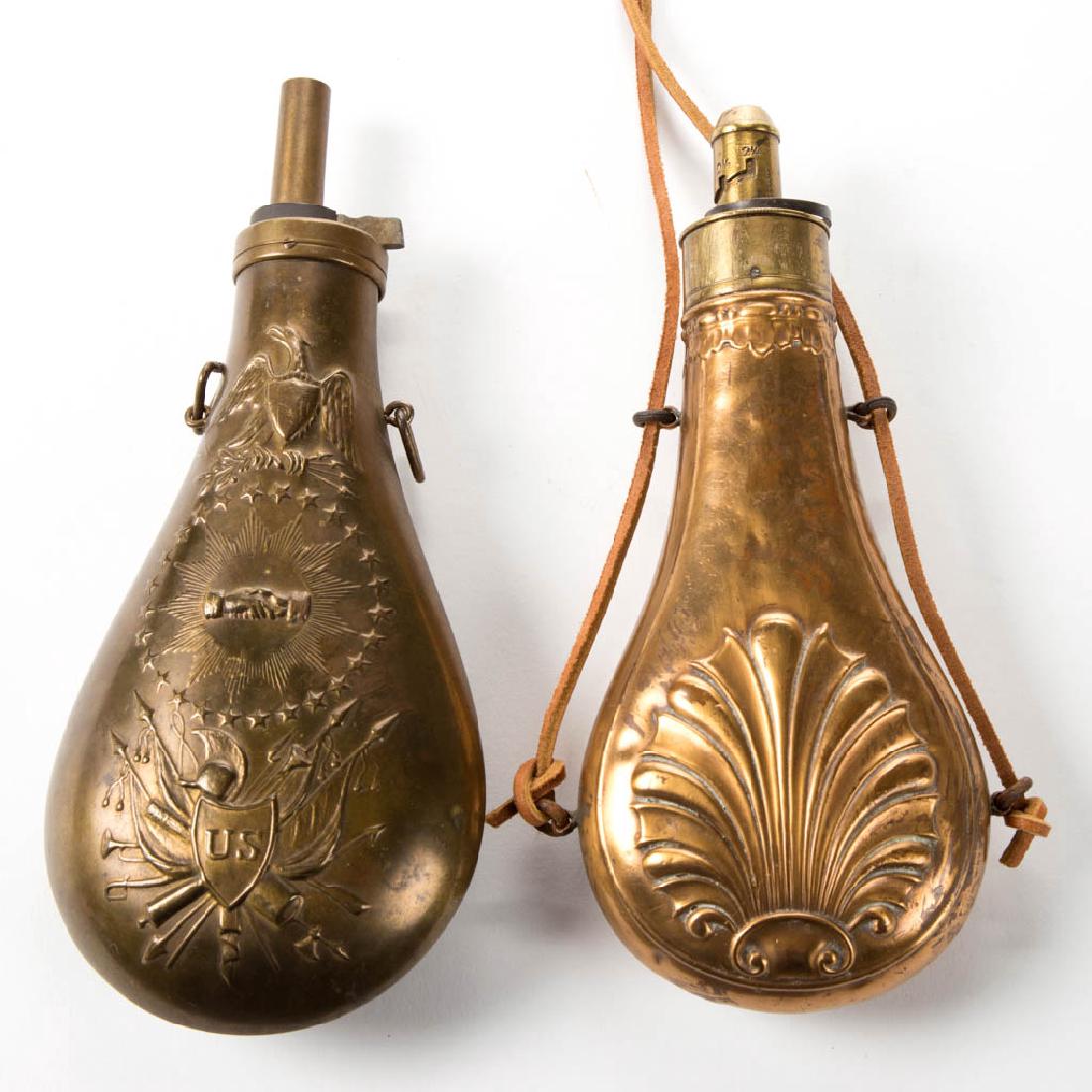 AMERICAN BRASS POWDER FLASKS, LOT OF TWO: AMERICAN BRASS POWDER FLASKS, LOT OF TWO comprising a Model 1855 "Peace and Friendship" example, and an example with embossed shell decoration to body, nozzle marked "J.W. HAWKLEY". 19th century. 8 1/