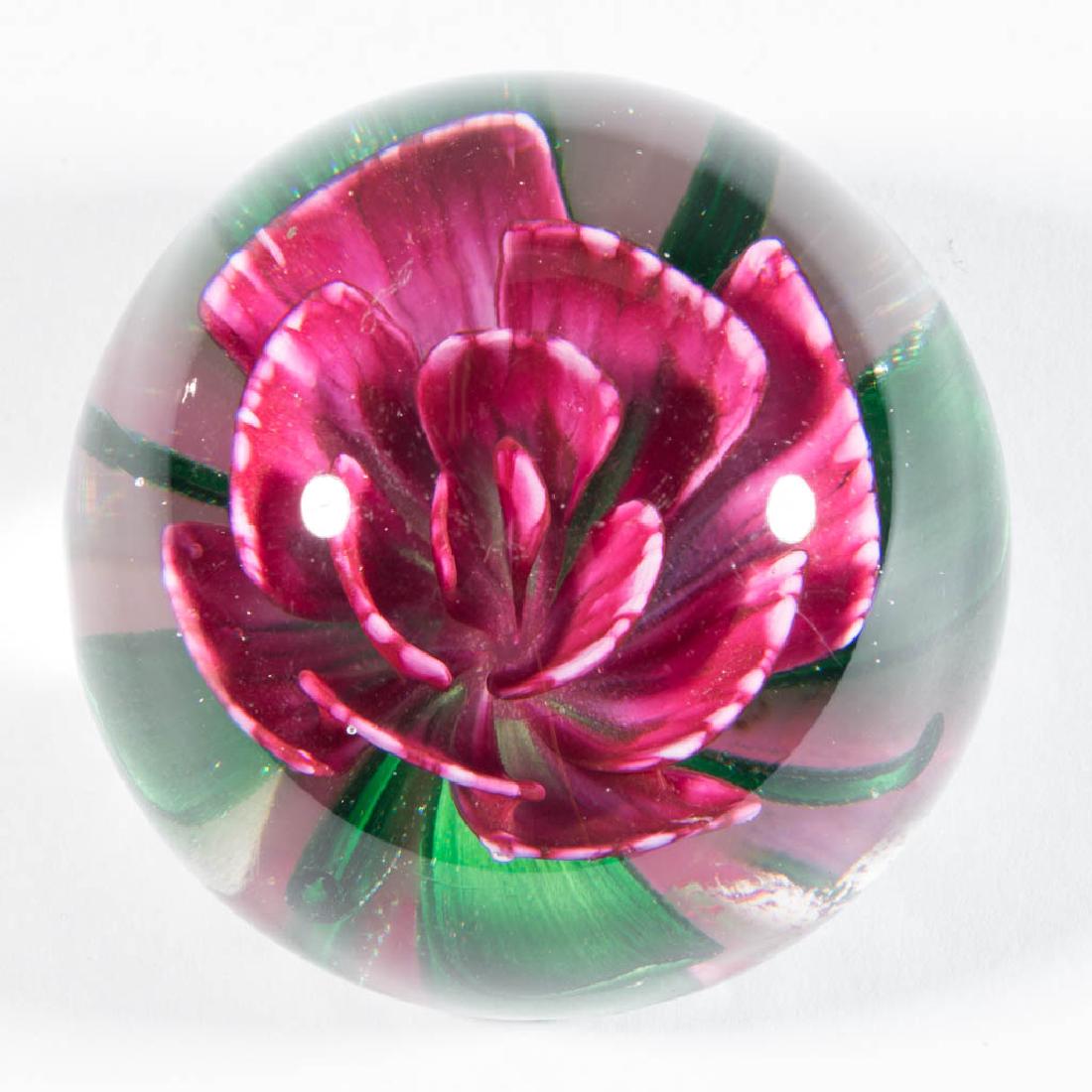 PAIRPOINT LAMPWORK PAPERWEIGHT: PAIRPOINT LAMPWORK PAPERWEIGHT, featuring a fuchsia and white narcissus with four wide and four narrow green leaves, facet-cut base edge. Circa 1974. 2" H, 2 5/8" D. Virtually undamaged with a couple 
