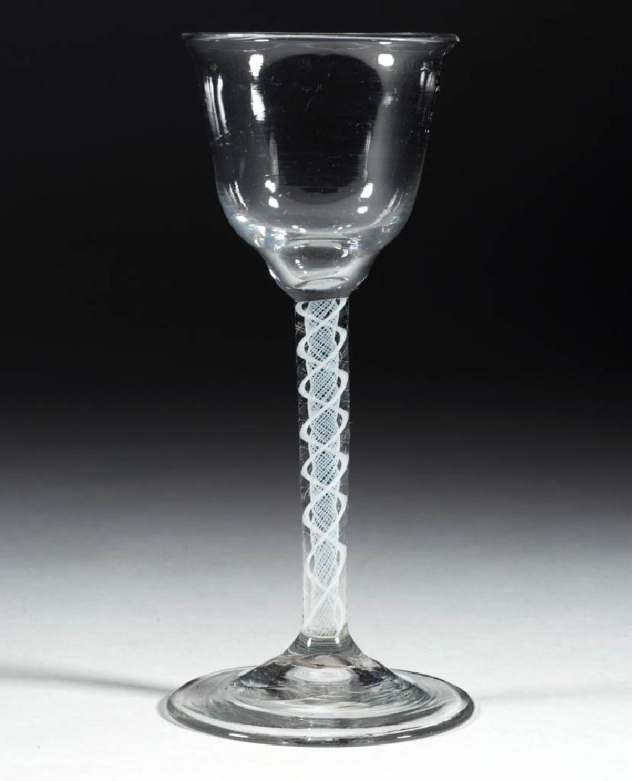 CONTINENTAL FREE-BLOWN OPAQUE-TWIST WINE GLASS: CONTINENTAL FREE-BLOWN OPAQUE-TWIST WINE GLASS, colorless non-lead glass, ogee bowl raised on a stem containing a pair of spiral threads outside gauze, conical foot with rough pontil mark. Circa 1750.