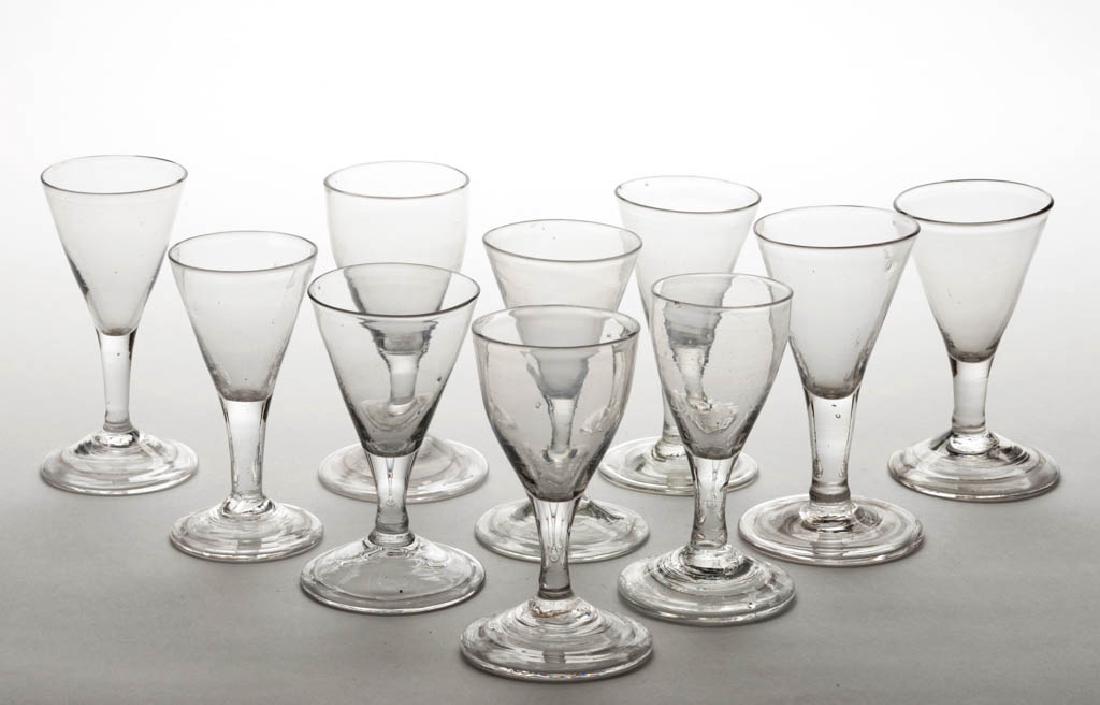 ASSORTED FREE-BLOWN WINE GLASSES, LOT OF TEN: ASSORTED FREE-BLOWN WINE GLASSES, LOT OF TEN, colorless lead glass, each raised on a drawn stem and folded foot with rough pontil mark. Late 18th/first quarter 19th century. 4 1/8" to 4 3/8" H. Undama