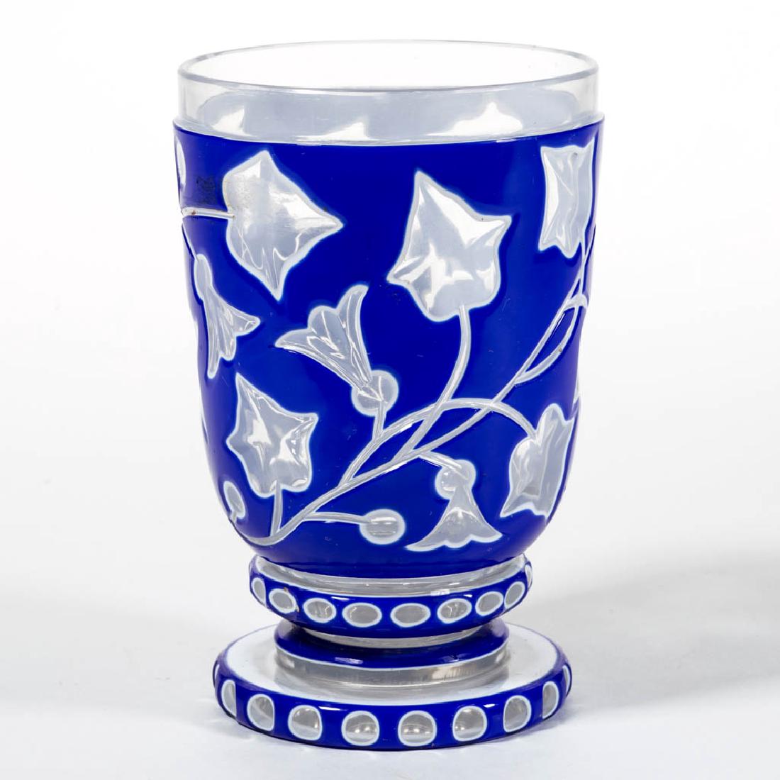 BOHEMIAN CUT DOUBLE-OVERLAY BEAKER / FOOTED TUMBLER: BOHEMIAN CUT DOUBLE-OVERLAY BEAKER / FOOTED TUMBLER, cobalt blue to white to colorless, floral decoration to the bowl with a band of punty cuts below, circular foot with a band of punty cuts to the ed